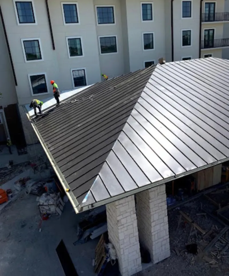 Crew installing standing seam metal roof panels on a commercial project in East Whittier